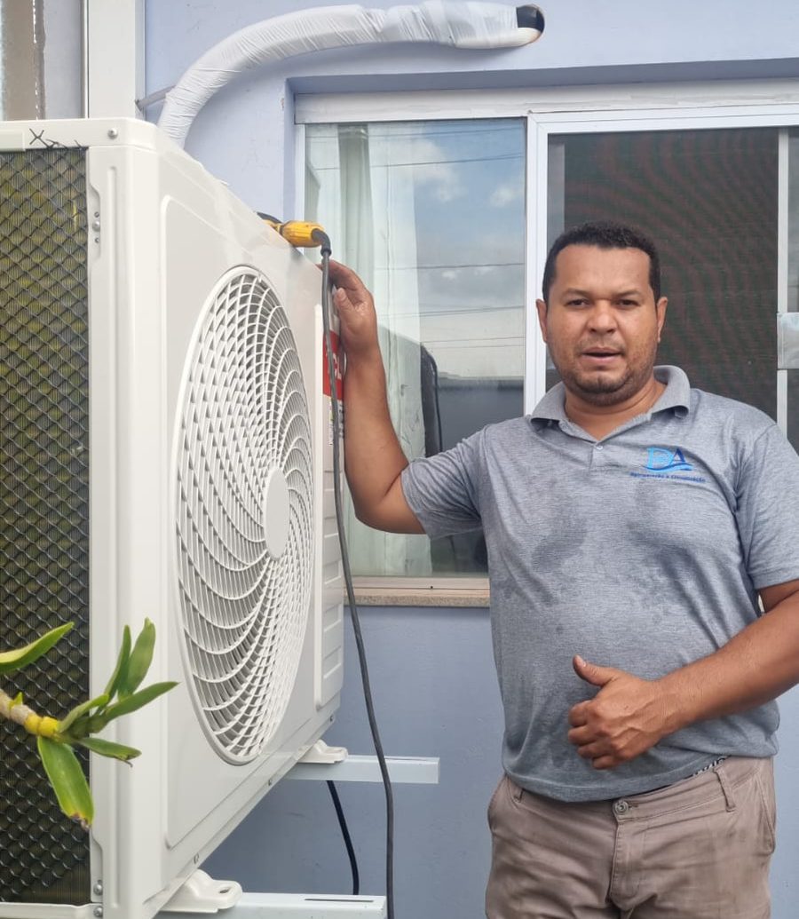 Deivid, técnico da D.A. Refrigeração, ao lado de condensadora de ar-condicionado recém-instalada